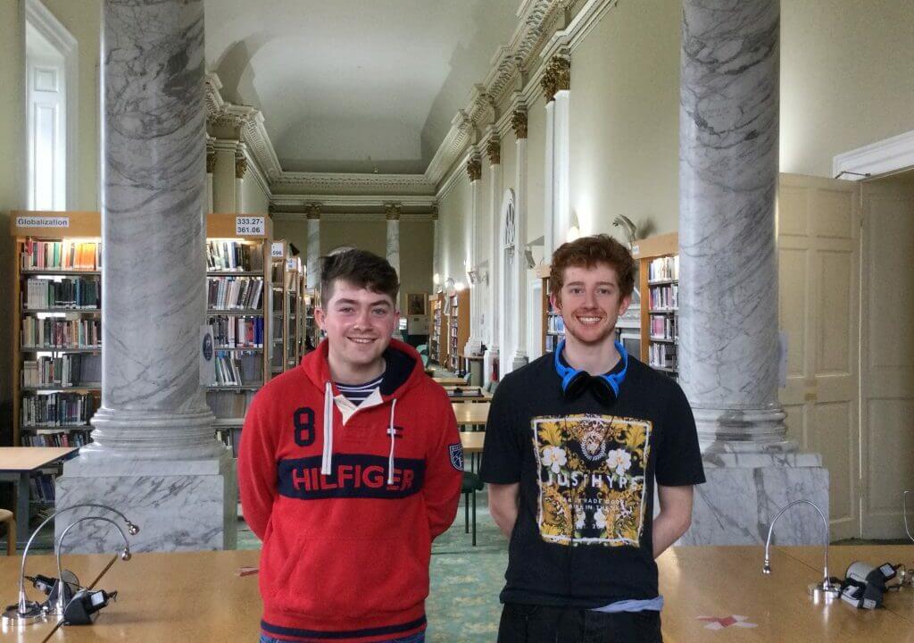 Two male students smiling in library