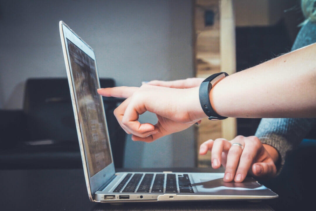 Close up of laptop with fingers pointing at screen