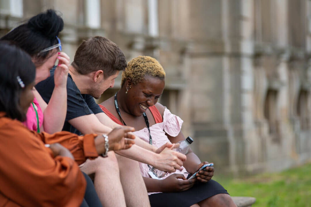 students sitting outdoors smiling