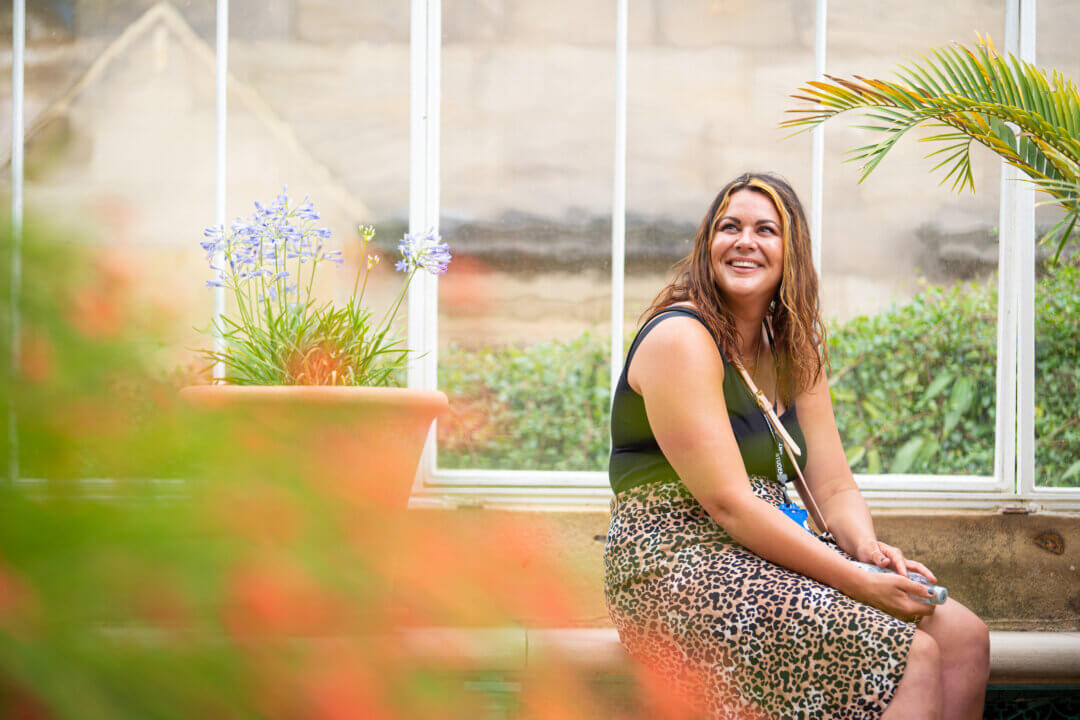 young woman smiling, sitting in conservatory